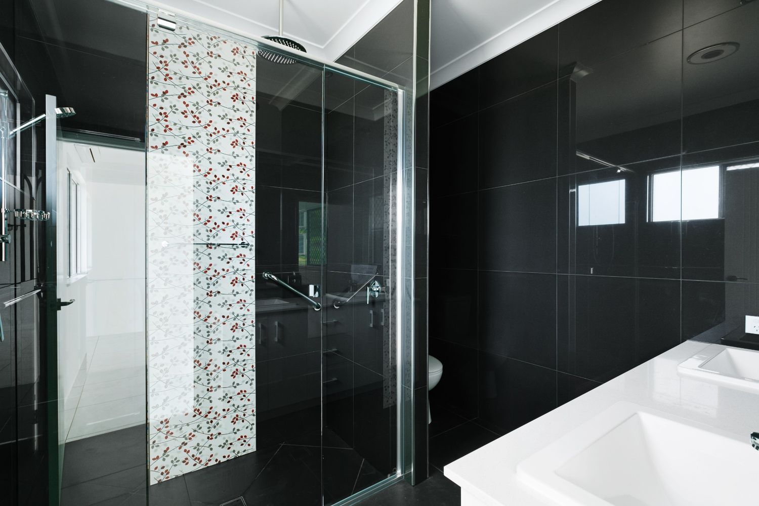 A Bathroom With Black Tiles and a Sliding Glass Shower Door — Ashlee Jones Homes in Gordonvale, QLD