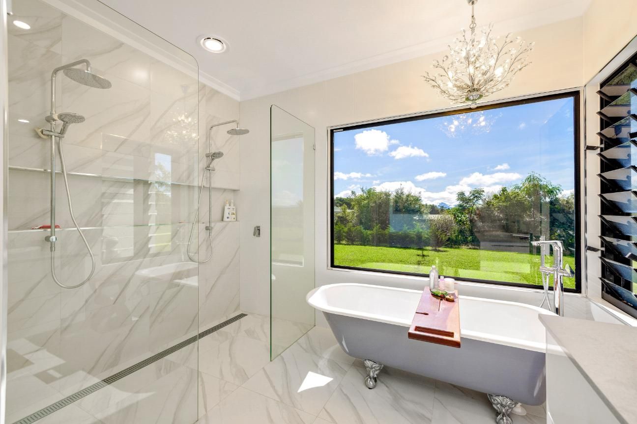 A Bathroom With a Bathtub, Shower, and Large Window — Ashlee Jones Homes in Gordonvale, QLD