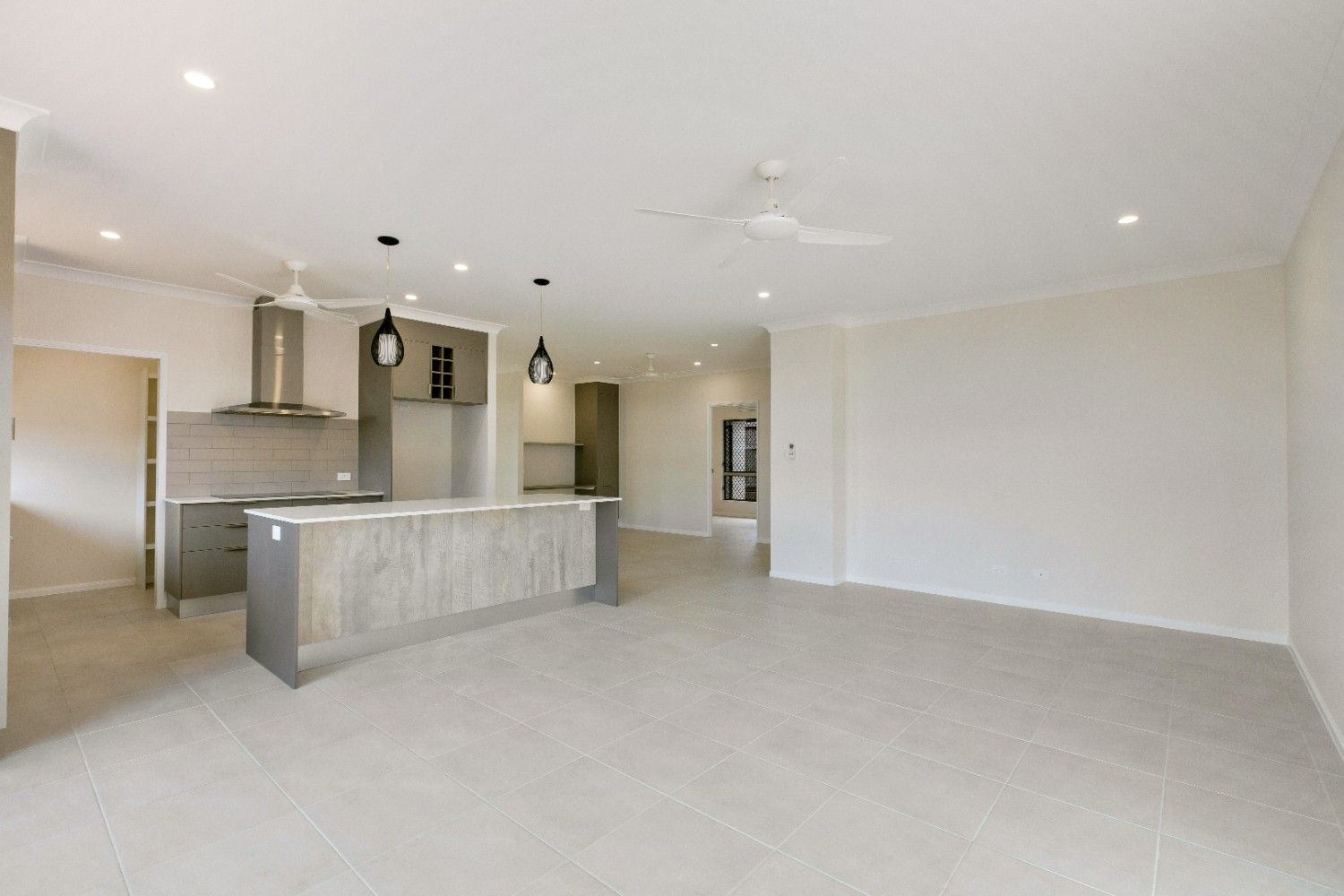 A Large Empty Room With a Kitchen and a Ceiling Fan — Ashlee Jones Homes in Gordonvale, QLD