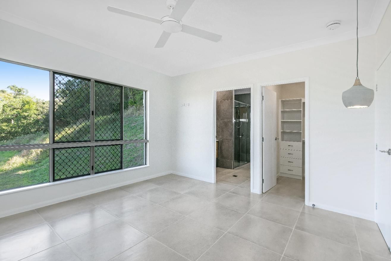 A Large Empty Room With a Ceiling Fan and Lots of Windows — Ashlee Jones Homes in Gordonvale, QLD