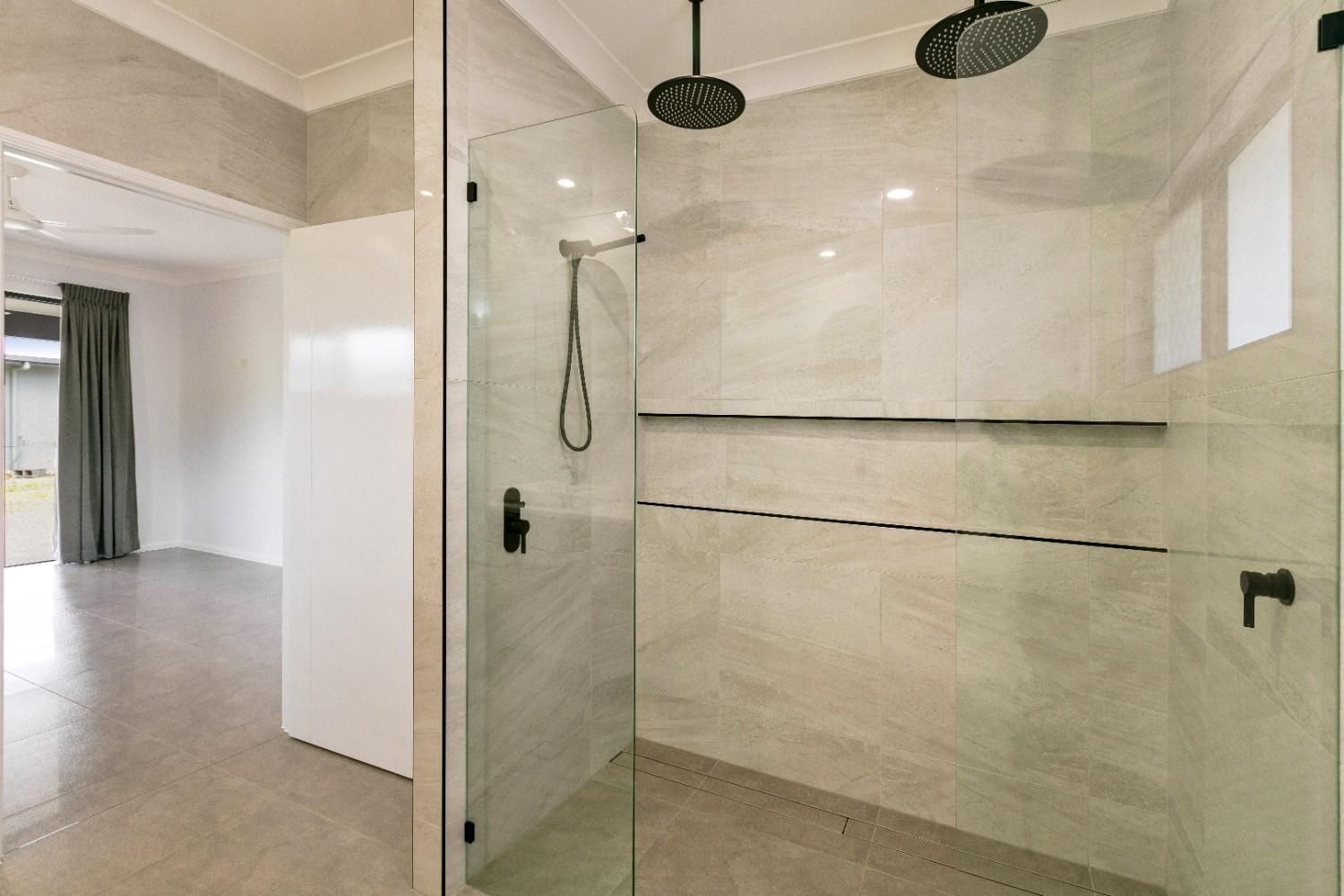 A Bathroom With a Walk in Shower With a Glass Door and a Shower Head — Ashlee Jones Homes in Gordonvale, QLD