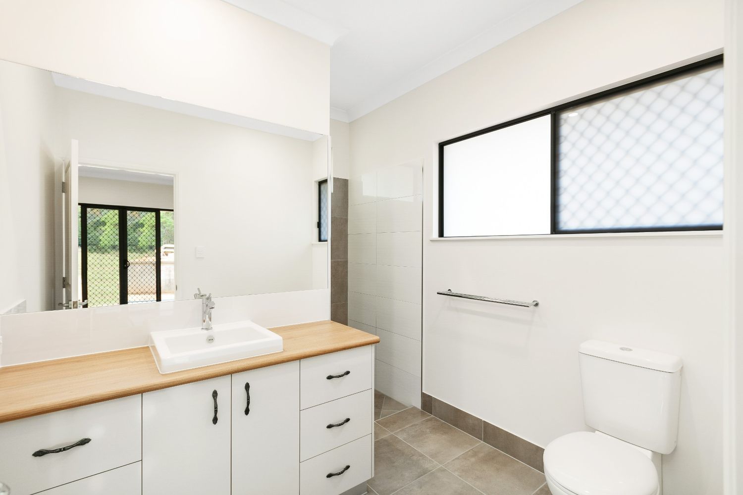 A Bathroom With a Sink, Toilet, Mirror and Window — Ashlee Jones Homes in Gordonvale, QLD