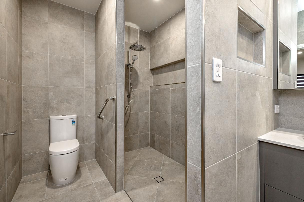 A Bathroom With a Toilet, Sink and Walk in Shower — Ashlee Jones Homes in Gordonvale, QLD