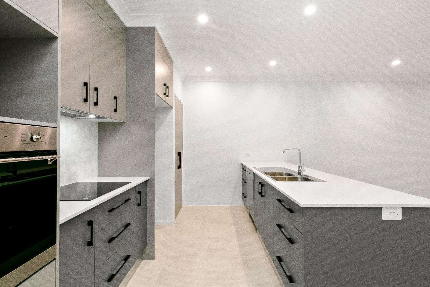 A Kitchen With Gray Cabinets and White Counter Tops — Ashlee Jones Homes in Gordonvale, QLD