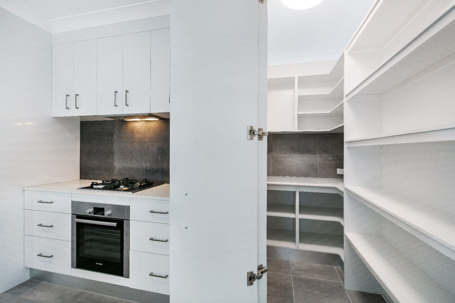 A Kitchen With White Cabinets and Shelves and a Stove Top Oven — Ashlee Jones Homes in Gordonvale, QLD
