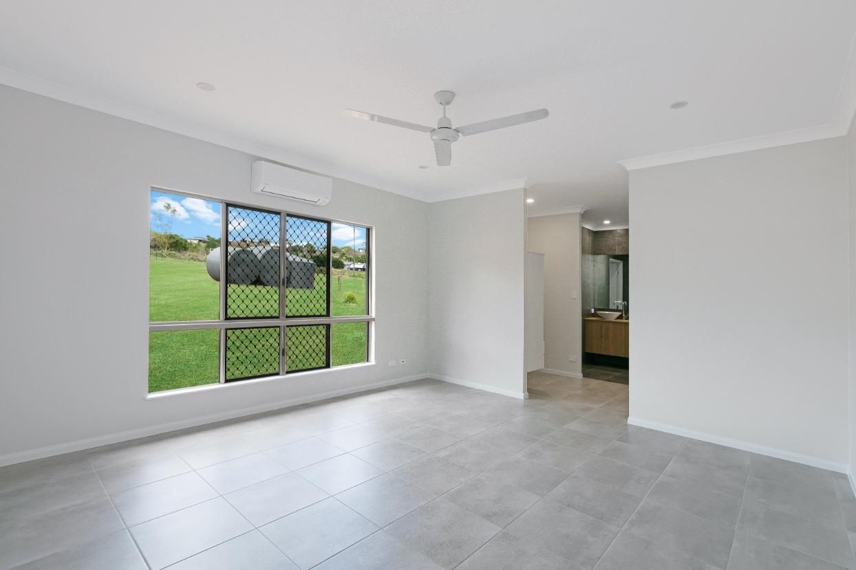 An Empty Living Room With a Ceiling Fan and a Large Window — Ashlee Jones Homes in Gordonvale, QLD