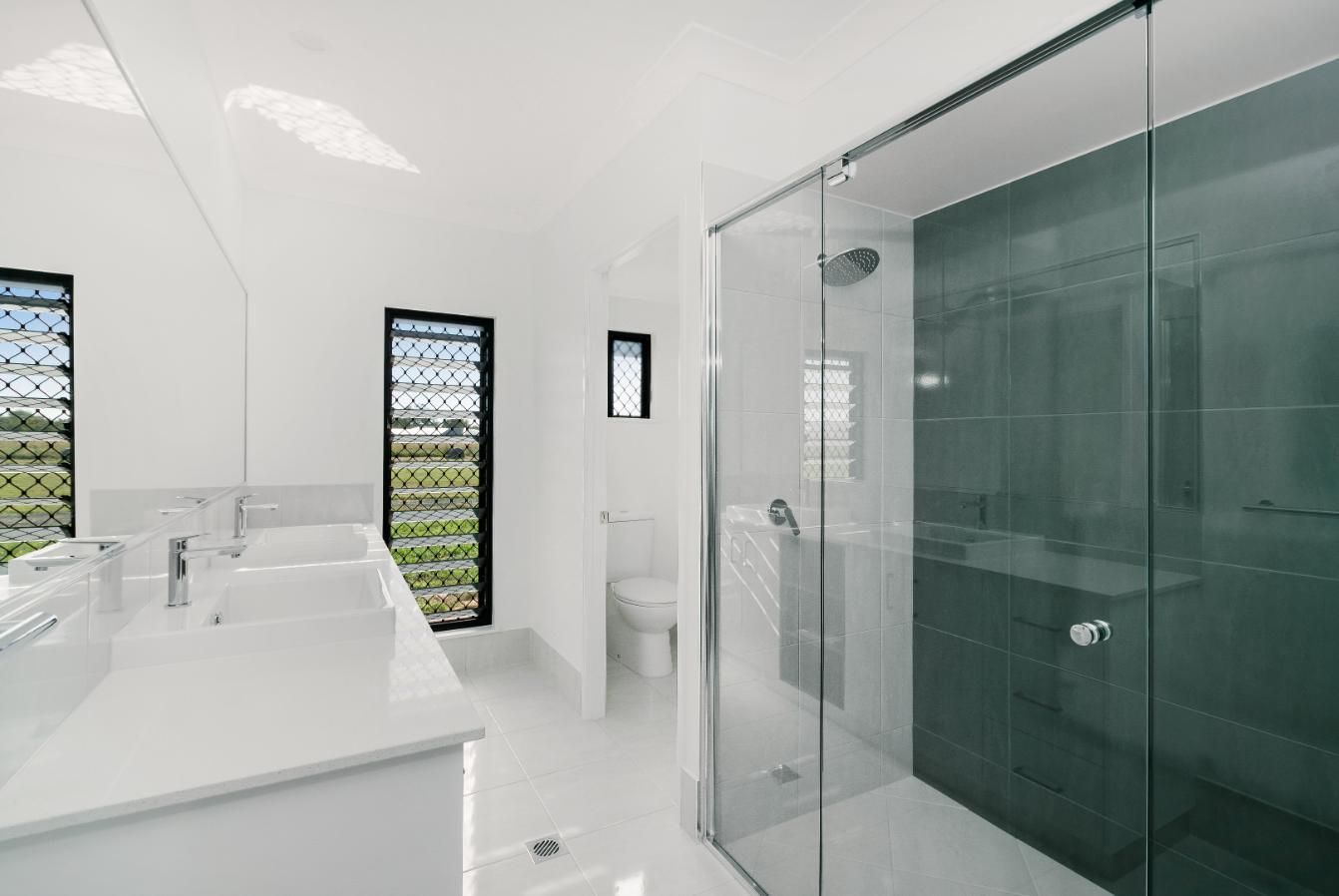 A Bathroom With a Sink, Toilet, Shower and Mirror — Ashlee Jones Homes in Gordonvale, QLD