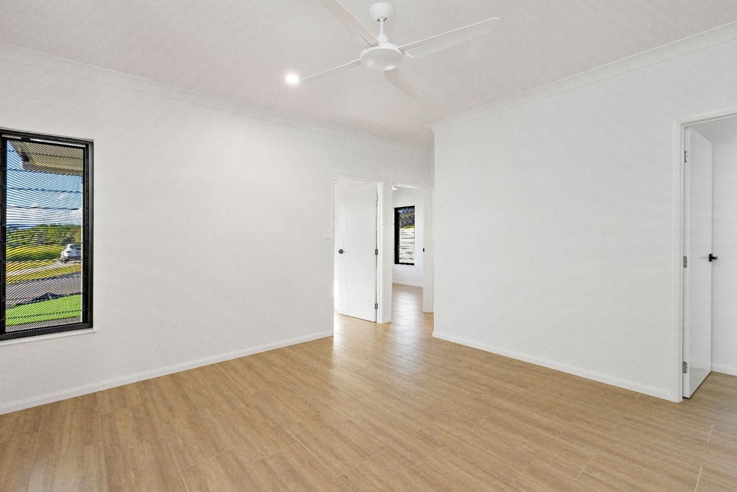 An Empty Room With Wooden Floors and a Ceiling Fan — Ashlee Jones Homes in Gordonvale, QLD