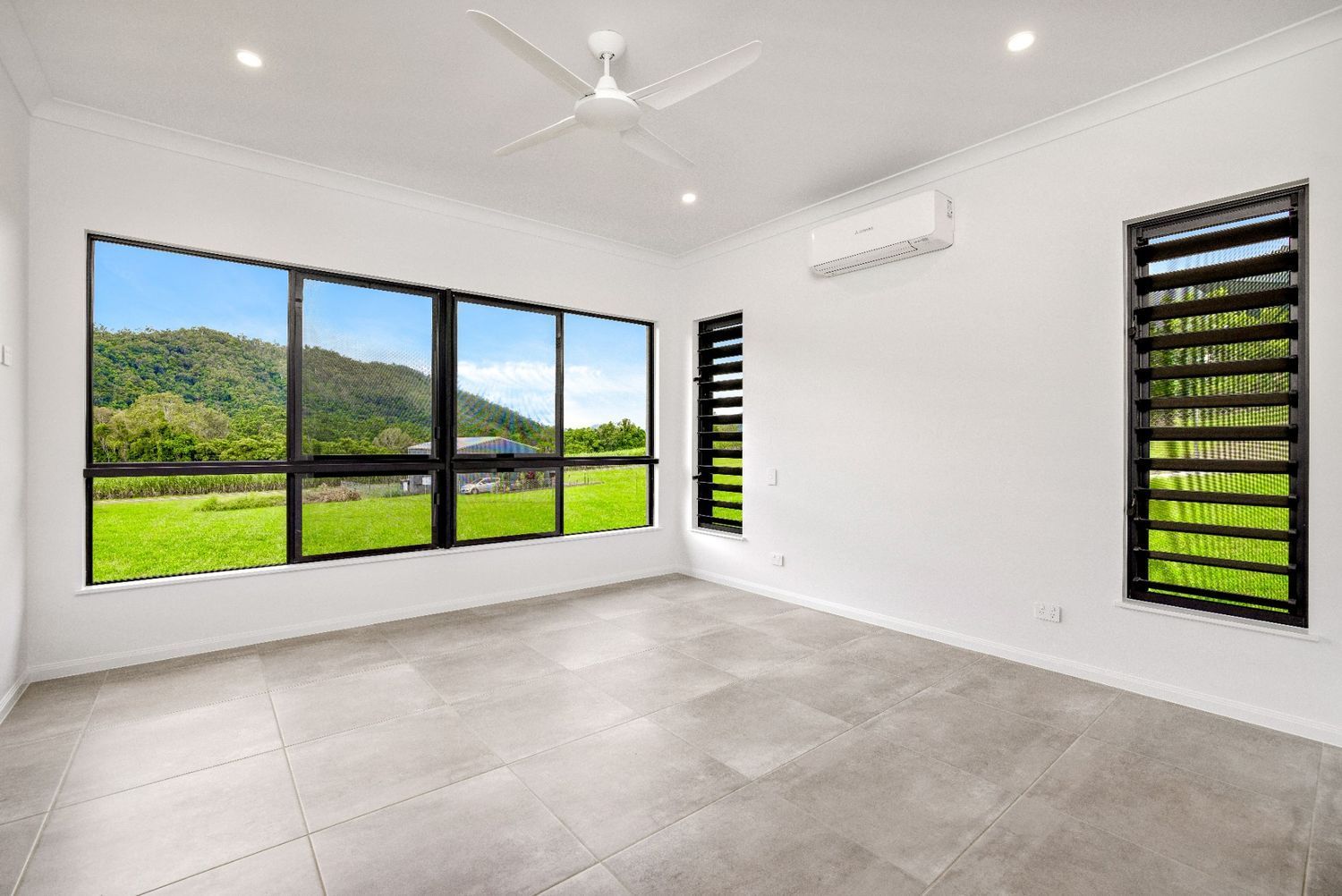 An Empty Room With a Lot of Windows and a Ceiling Fan — Ashlee Jones Homes in Gordonvale, QLD