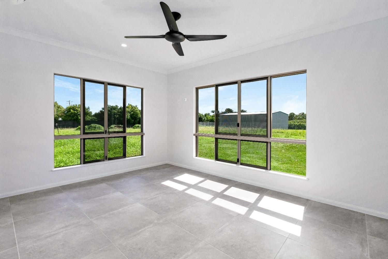 An Empty Room With a Ceiling Fan and Lots of Windows — Ashlee Jones Homes in Gordonvale, QLD