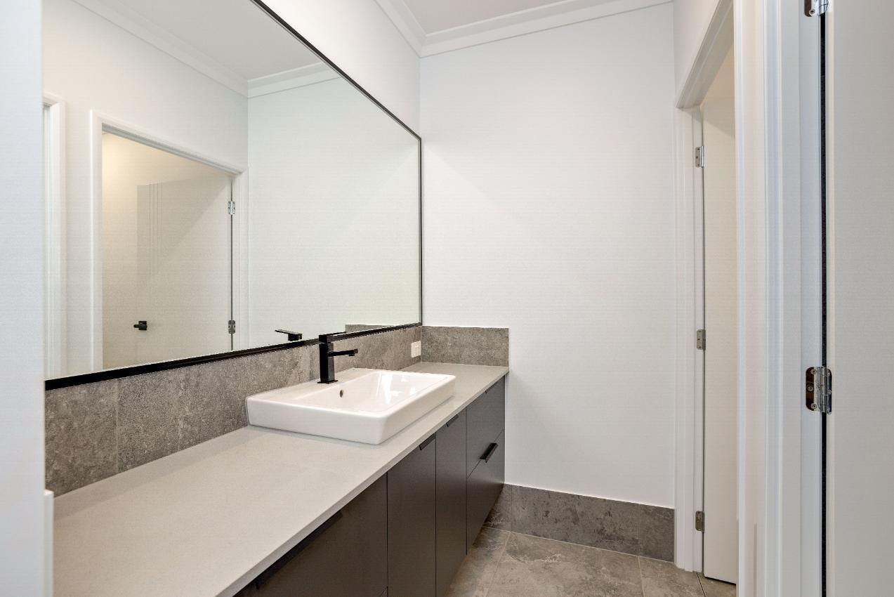 A Bathroom With a Sink and a Large Mirror — Ashlee Jones Homes in Gordonvale, QLD