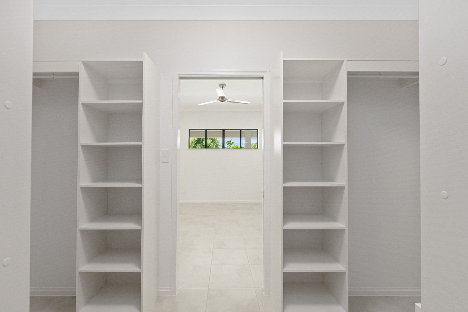 A Walk in Closet With Shelves and a Door Leading to a Bedroom — Ashlee Jones Homes in Gordonvale, QLD