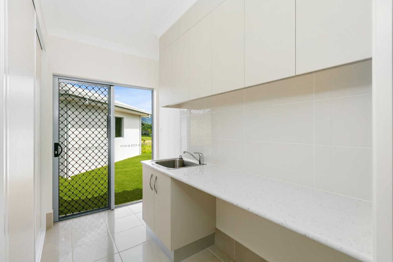 A Kitchen With White Cabinets, a Sink, and a Sliding Glass Door — Ashlee Jones Homes in Gordonvale, QLD