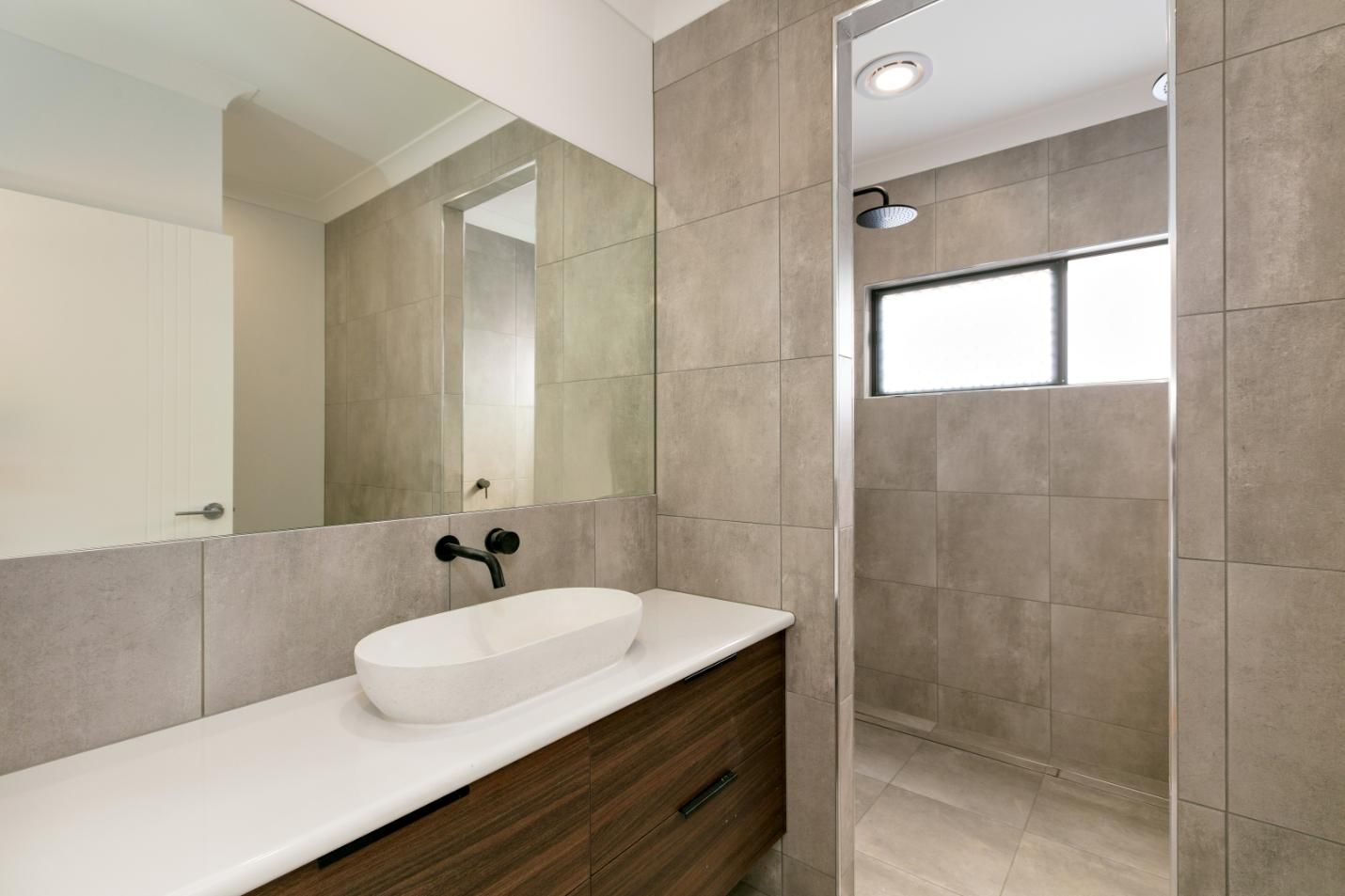 A Bathroom With a Sink, Mirror and Shower — Ashlee Jones Homes in Gordonvale, QLD