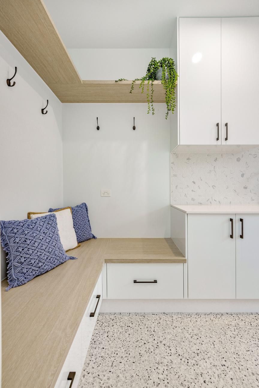 A Laundry Room With a Bench and White Cabinets — Ashlee Jones Homes in Gordonvale, QLD