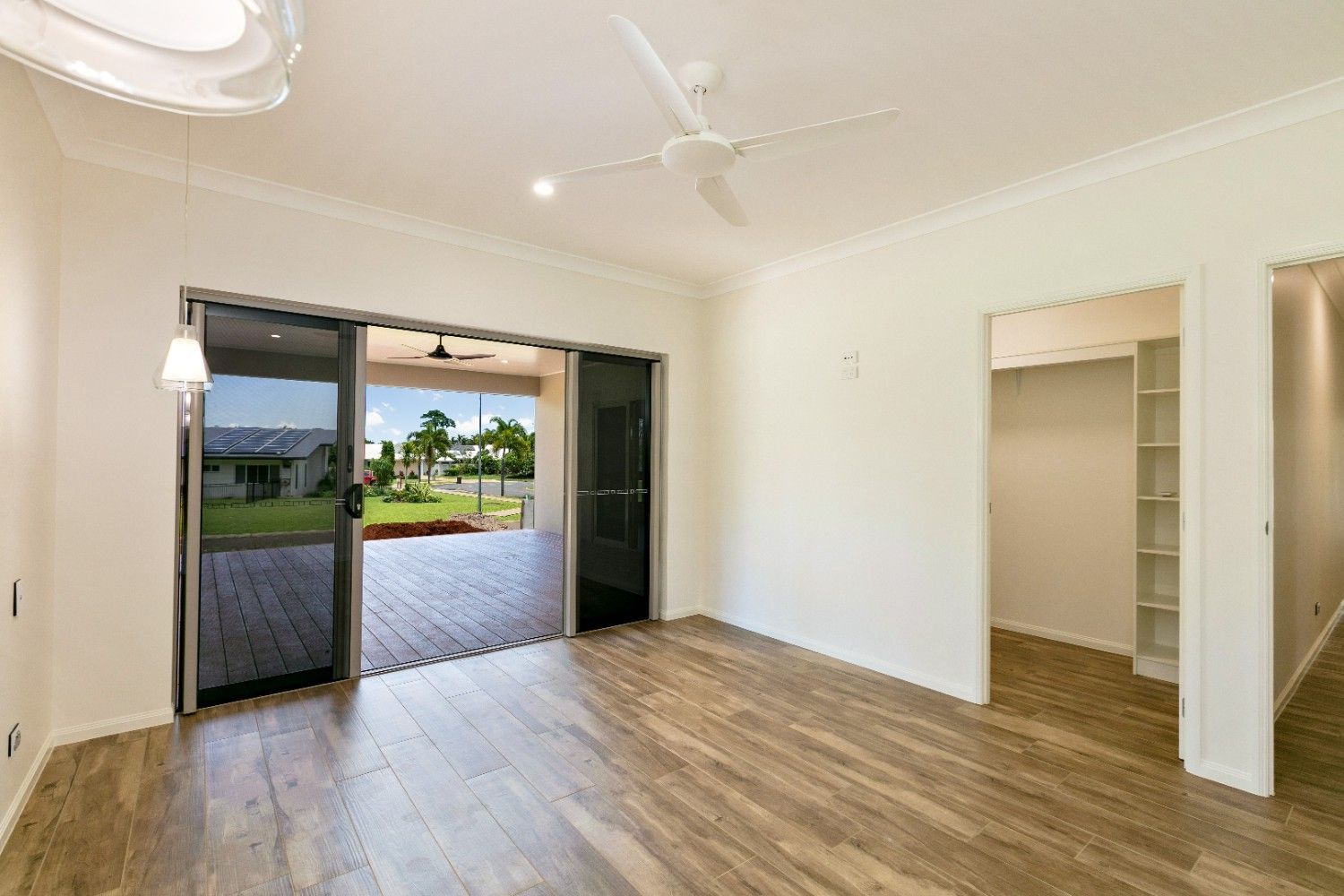 A Living Room With Hardwood Floors and a Ceiling Fan — Ashlee Jones Homes in Gordonvale, QLD