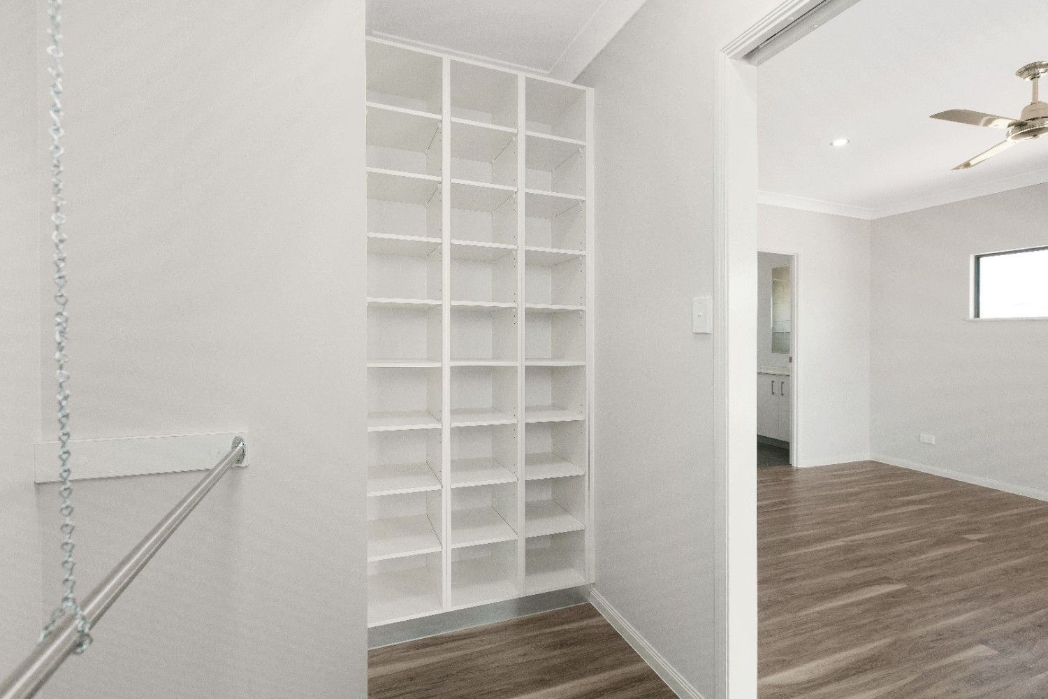 An Empty Living Room With Hardwood Floors and a Ceiling Fan — Ashlee Jones Homes in Gordonvale, QLD