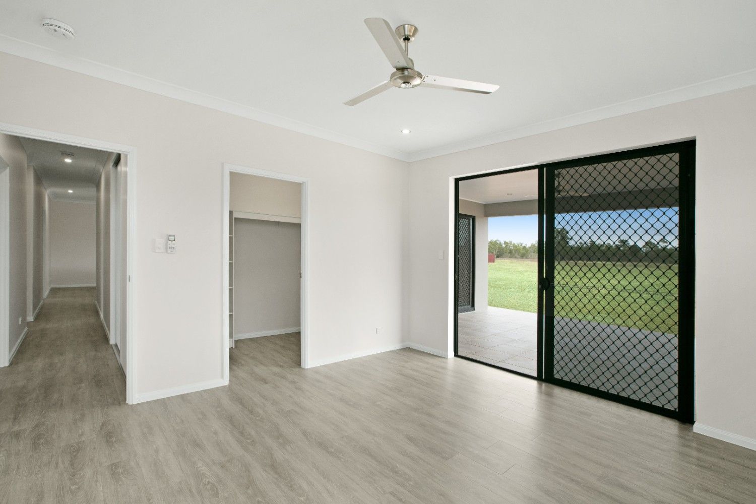An Empty Living Room With a Ceiling Fan and Sliding Glass Doors — Ashlee Jones Homes in Gordonvale, QLD
