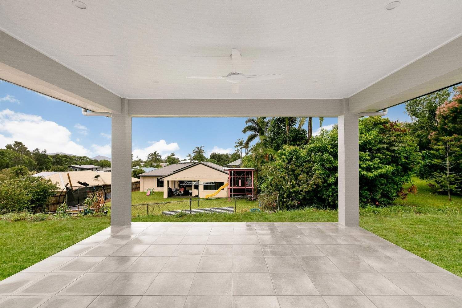 An Empty Patio With a Ceiling Fan and a View of a House — Ashlee Jones Homes in Gordonvale, QLD