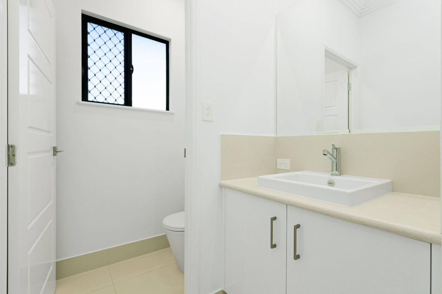 A Bathroom With a Sink, Toilet, Mirror and Window — Ashlee Jones Homes in Gordonvale, QLD