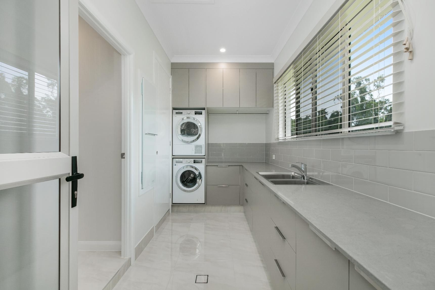 A Laundry Room With a Washer and Dryer Stacked on Top of Each Other — Ashlee Jones Homes in Gordonvale, QLD