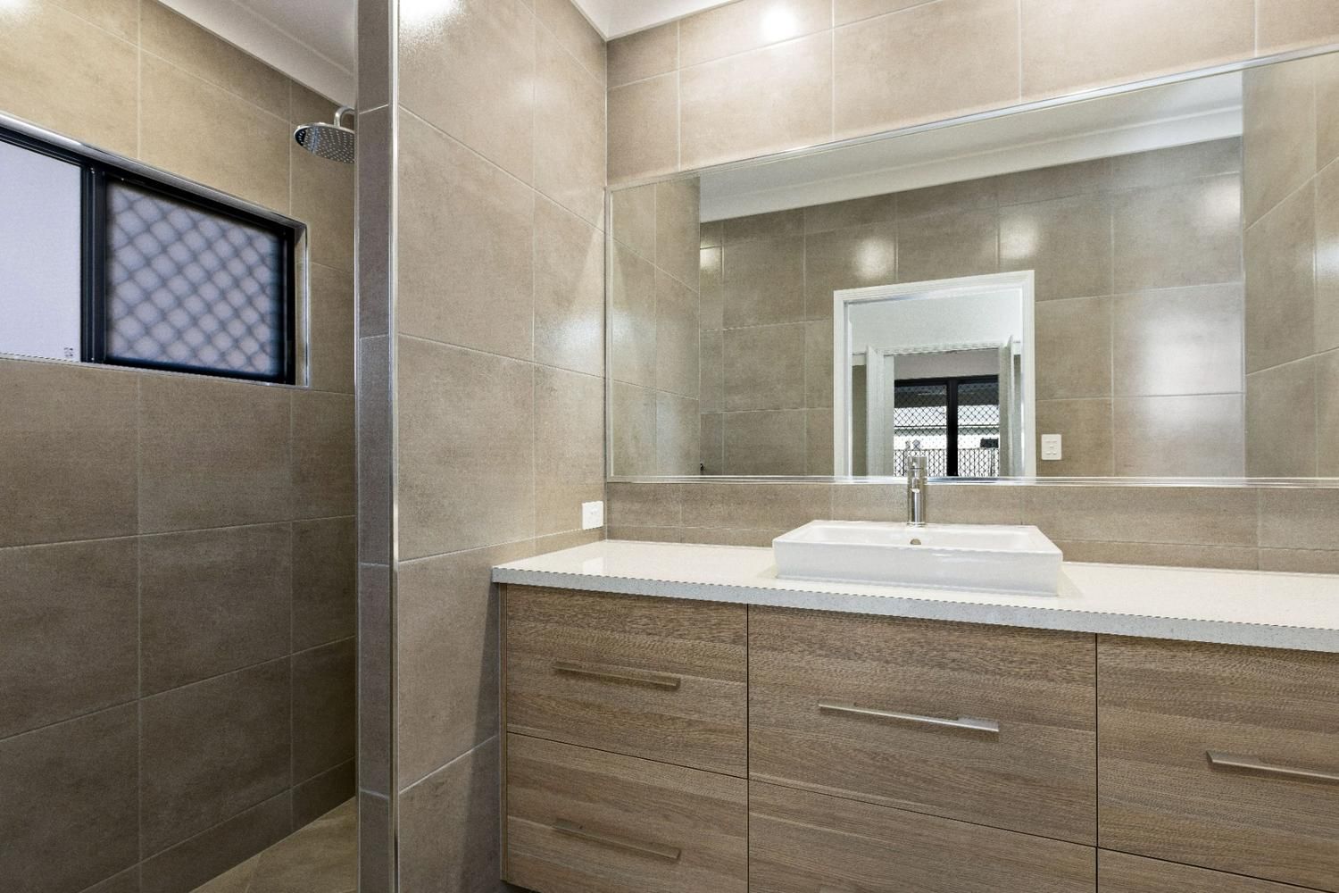 A Bathroom With a Sink, Mirror and Walk in Shower — Ashlee Jones Homes in Gordonvale, QLD