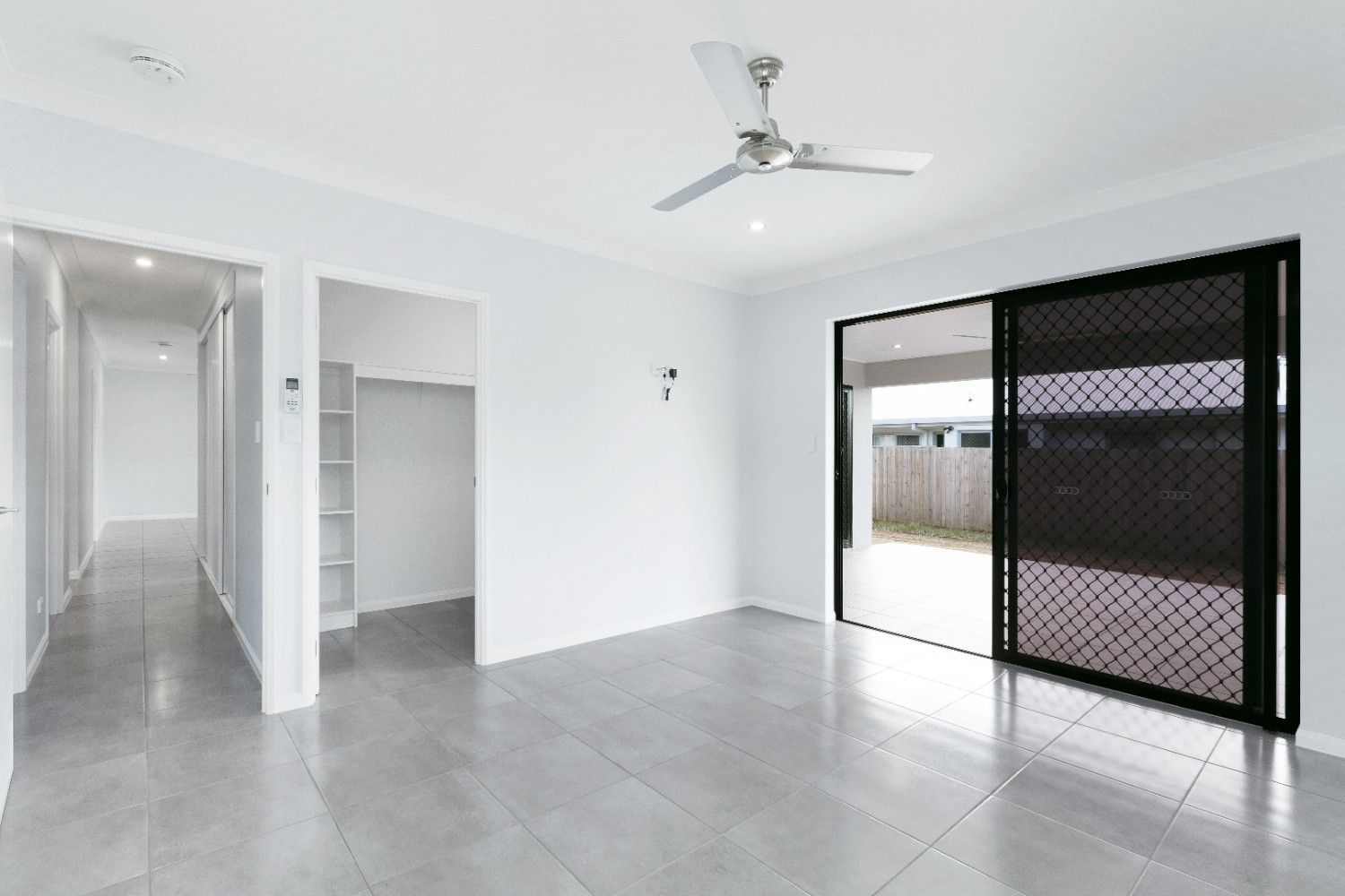 An Empty Living Room With a Ceiling Fan and Sliding Glass Doors — Ashlee Jones Homes in Gordonvale, QLD