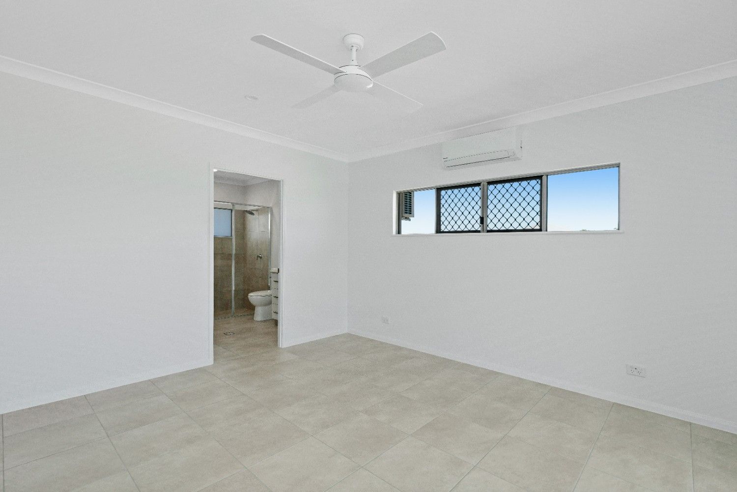 An Empty Bedroom With a Ceiling Fan and a Window — Ashlee Jones Homes in Gordonvale, QLD