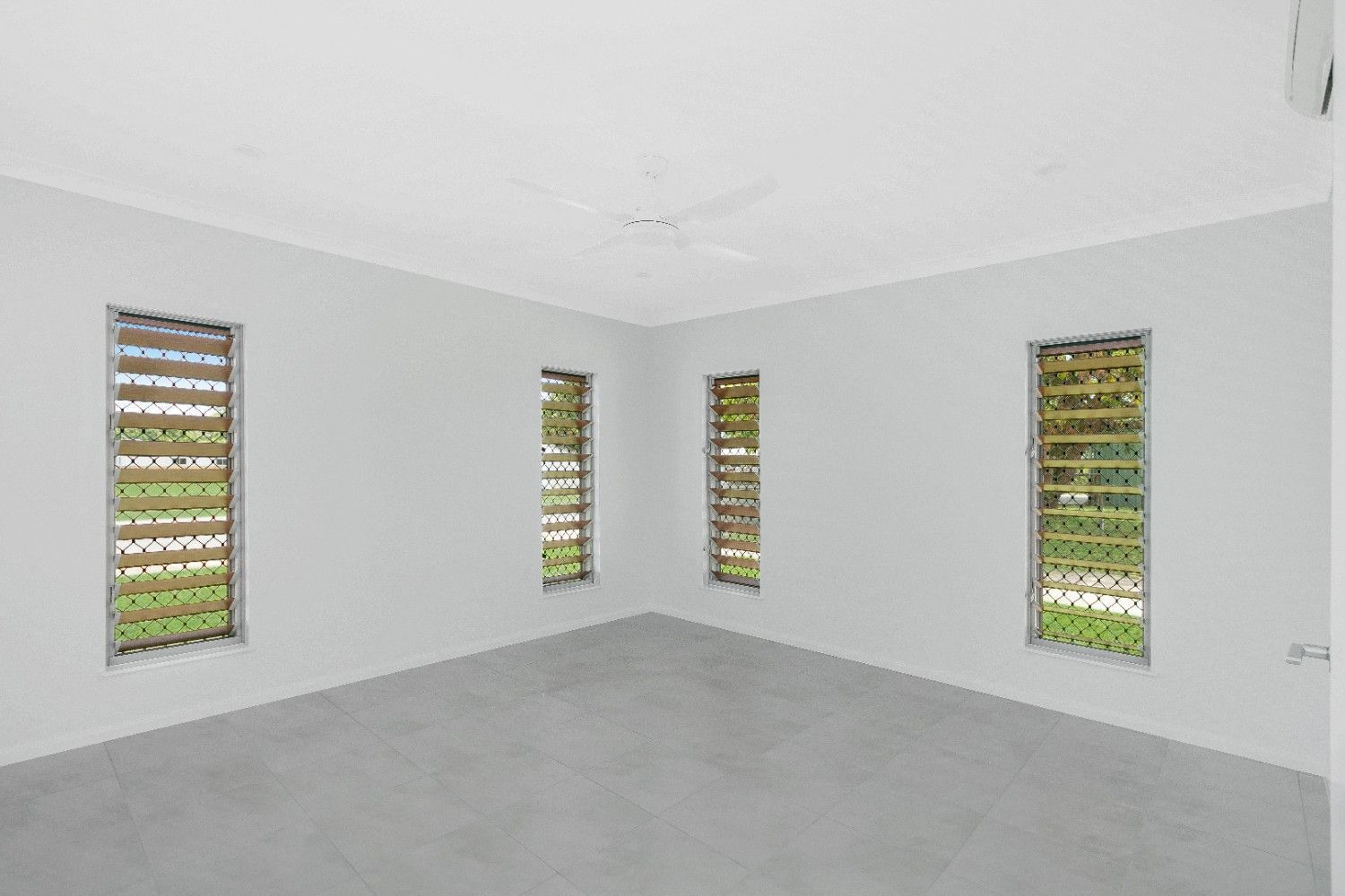 An Empty Room With Three Windows and a Ceiling Fan — Ashlee Jones Homes in Gordonvale, QLD