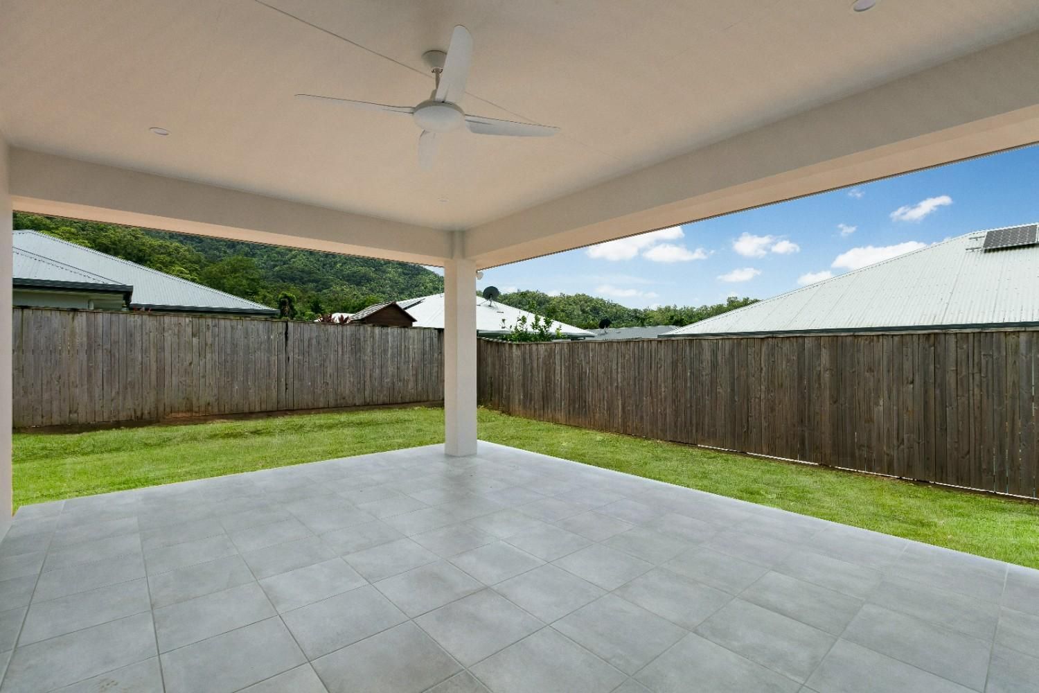 An Empty Patio With a Ceiling Fan and a Wooden Fence in the Background — Ashlee Jones Homes in Gordonvale, QLD