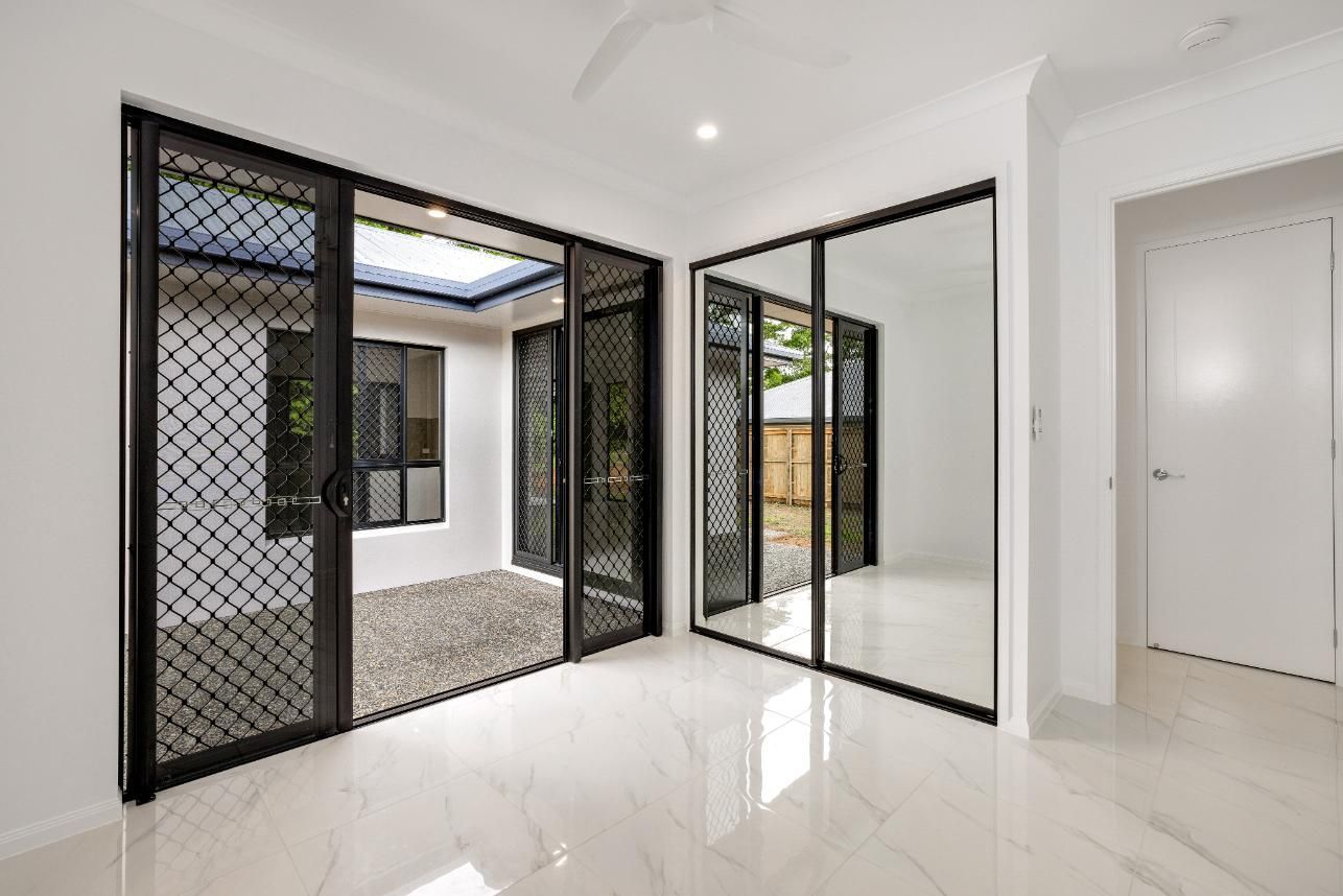 An Empty Room With Sliding Glass Doors and Mirrored Walls — Ashlee Jones Homes in Gordonvale, QLD
