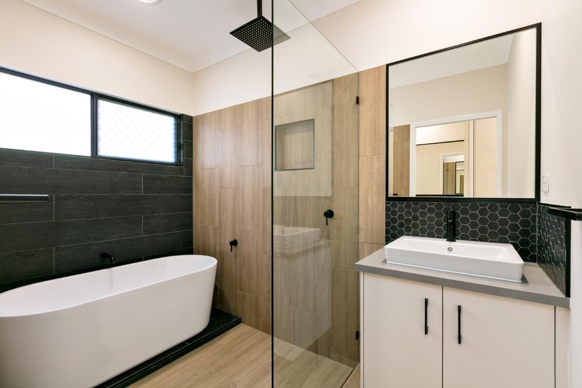 A Bathroom With a Bathtub, Sink, Mirror and Walk in Shower — Ashlee Jones Homes in Gordonvale, QLD