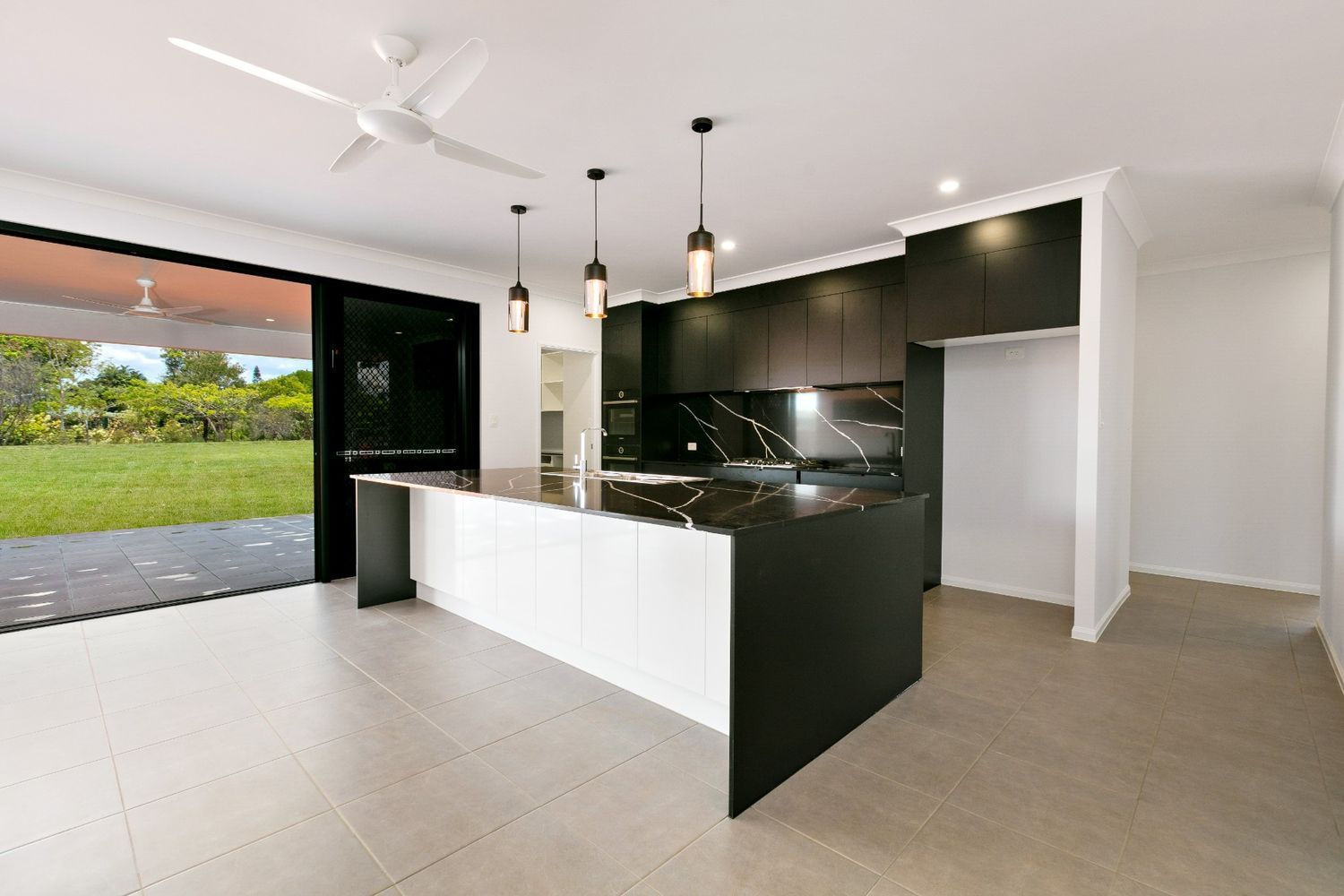An Empty Kitchen With a Large Island and a Ceiling Fan — Ashlee Jones Homes in Gordonvale, QLD