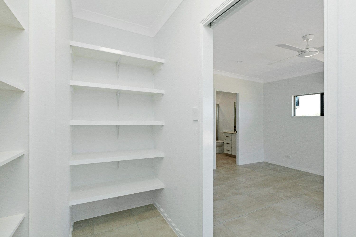 A Walk in Closet With Shelves and a Ceiling Fan in a House — Ashlee Jones Homes in Gordonvale, QLD