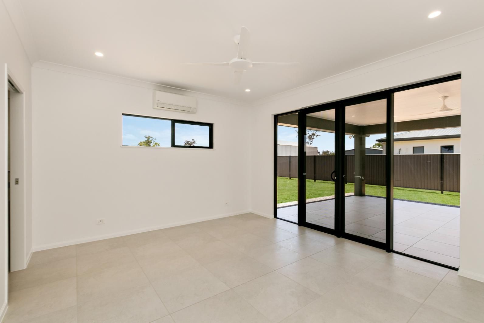An Empty Room With Sliding Glass Doors and a Ceiling Fan — Ashlee Jones Homes in Gordonvale, QLD