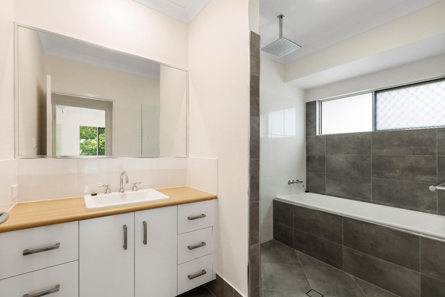 A Bathroom With a Sink, Mirror and Bathtub — Ashlee Jones Homes in Gordonvale, QLD