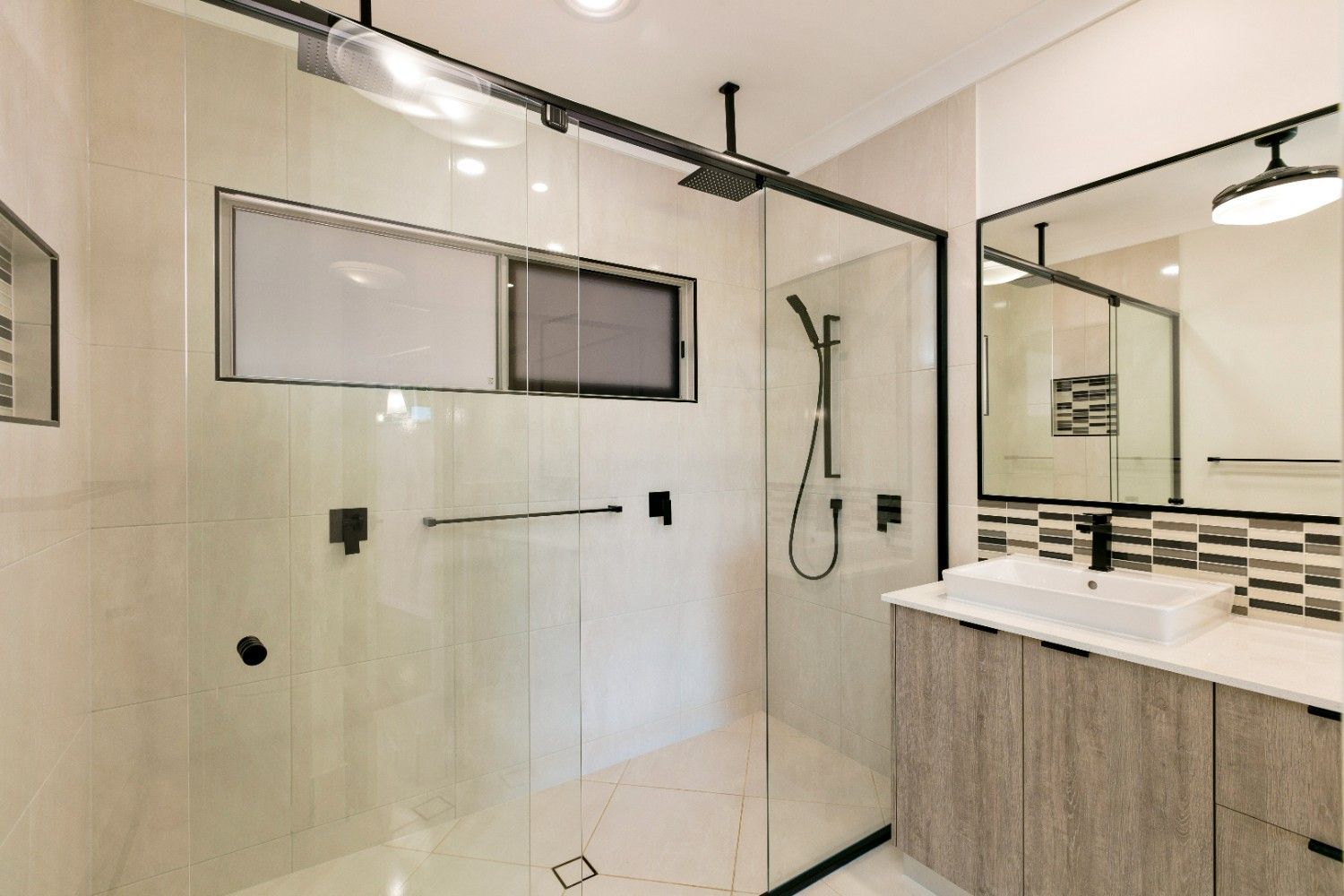 A Bathroom With a Walk in Shower, Sink and Mirror — Ashlee Jones Homes in Gordonvale, QLD