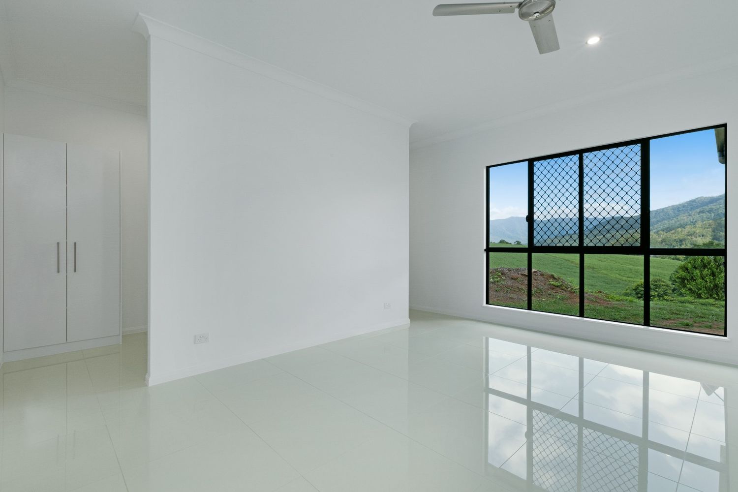 An Empty Room With Two Windows and a Ceiling Fan — Ashlee Jones Homes in Gordonvale, QLD