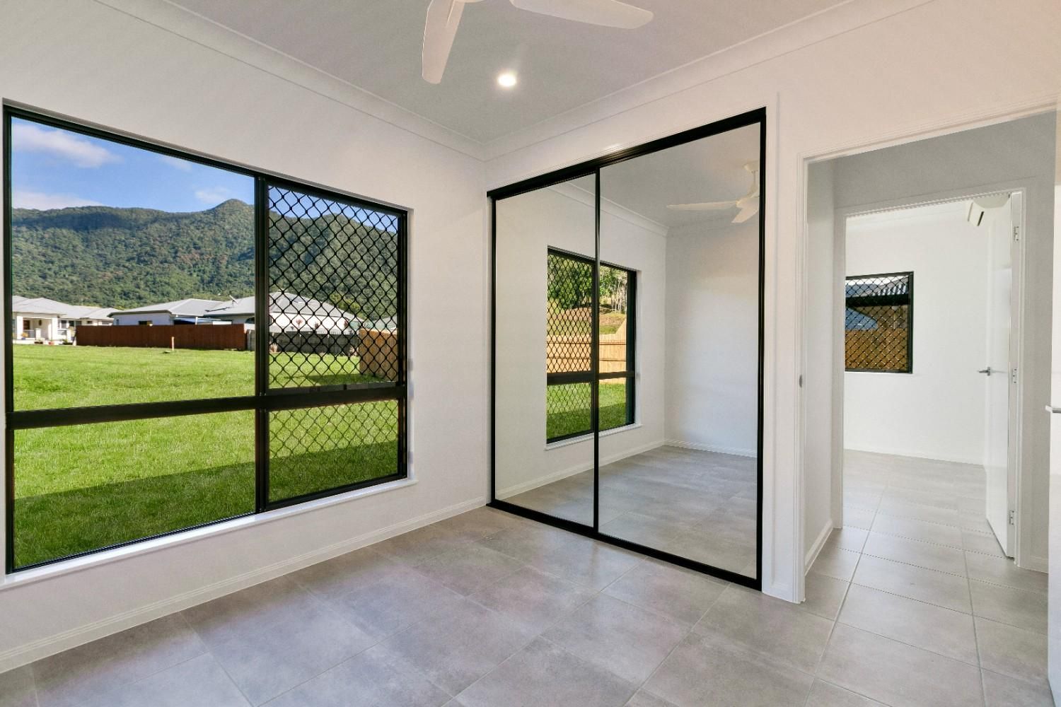 A Bedroom With Sliding Glass Doors and a Ceiling Fan  — Ashlee Jones Homes in Gordonvale, QLD