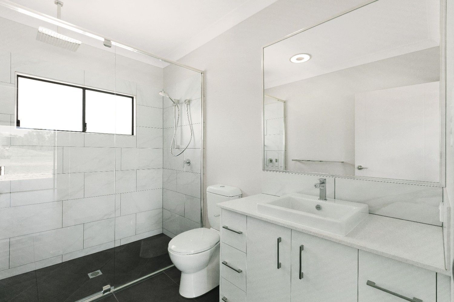 A Bathroom With a Toilet, Sink, Mirror and Shower — Ashlee Jones Homes in Gordonvale, QLD