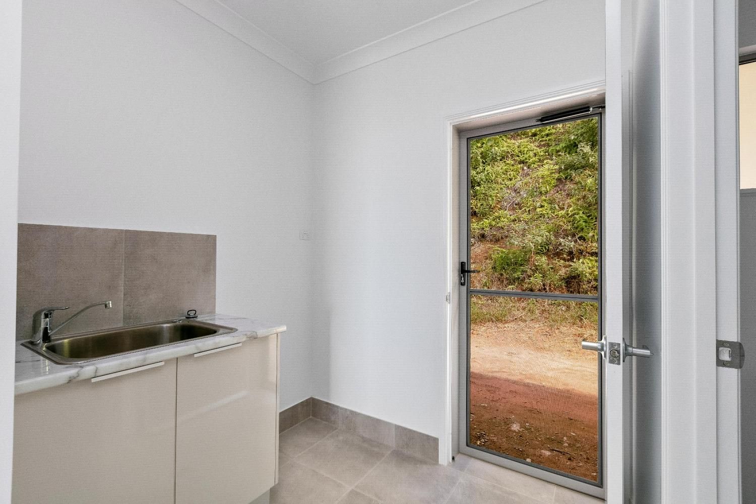 A Laundry Room With a Sink, Cabinets, and a Door — Ashlee Jones Homes in Gordonvale, QLD
