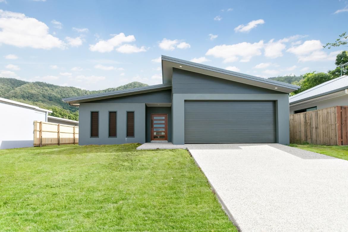 A Modern House With a Large Garage and a Driveway in Front of It — Ashlee Jones Homes in Gordonvale, QLD