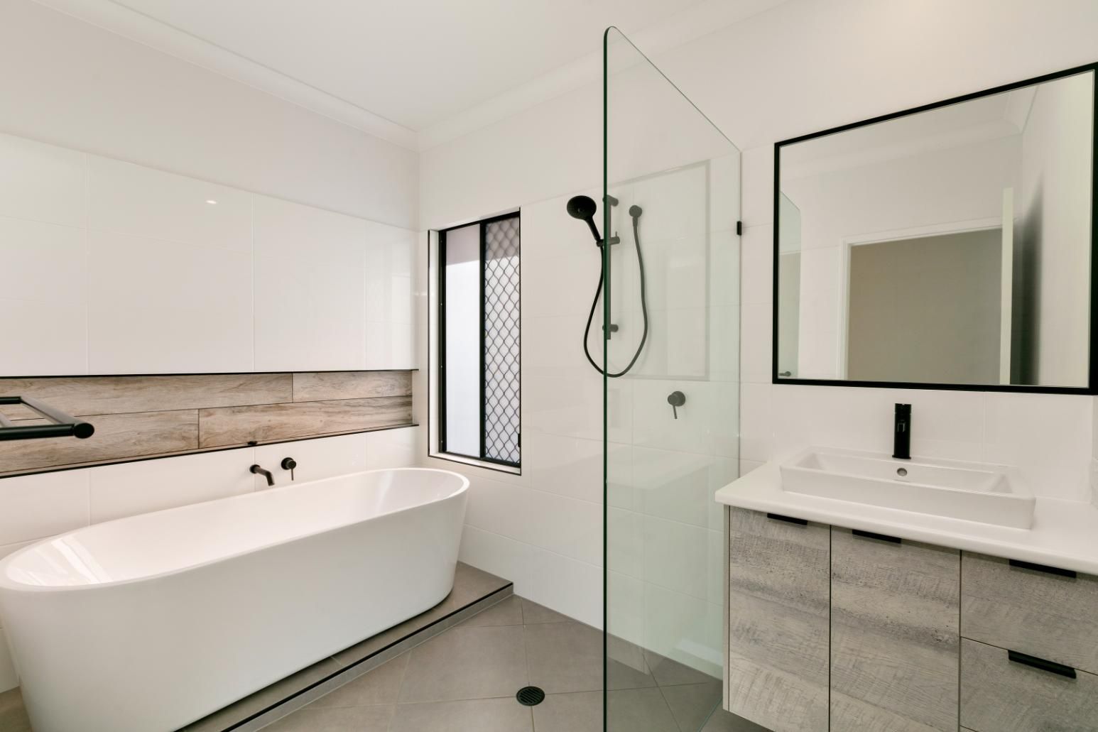 A Bathroom With a Bathtub, Sink, Shower and Mirror — Ashlee Jones Homes in Gordonvale, QLD