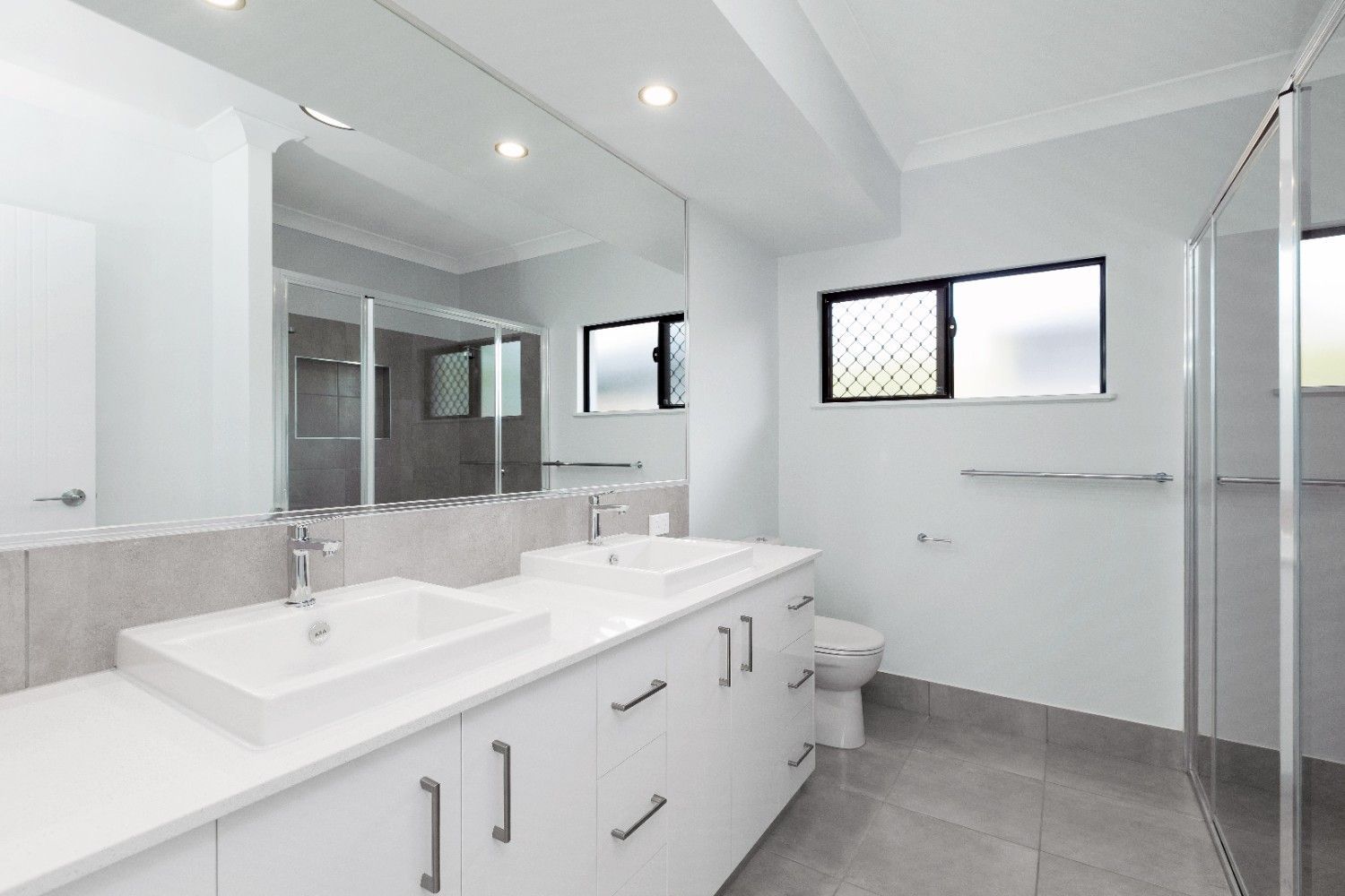 A Bathroom With Two Sinks, a Toilet, and a Large Mirror — Ashlee Jones Homes in Gordonvale, QLD