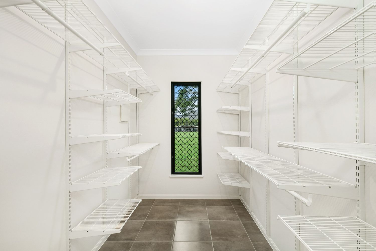 A Walk in Closet With Lots of Shelves and a Window — Ashlee Jones Homes in Gordonvale, QLD