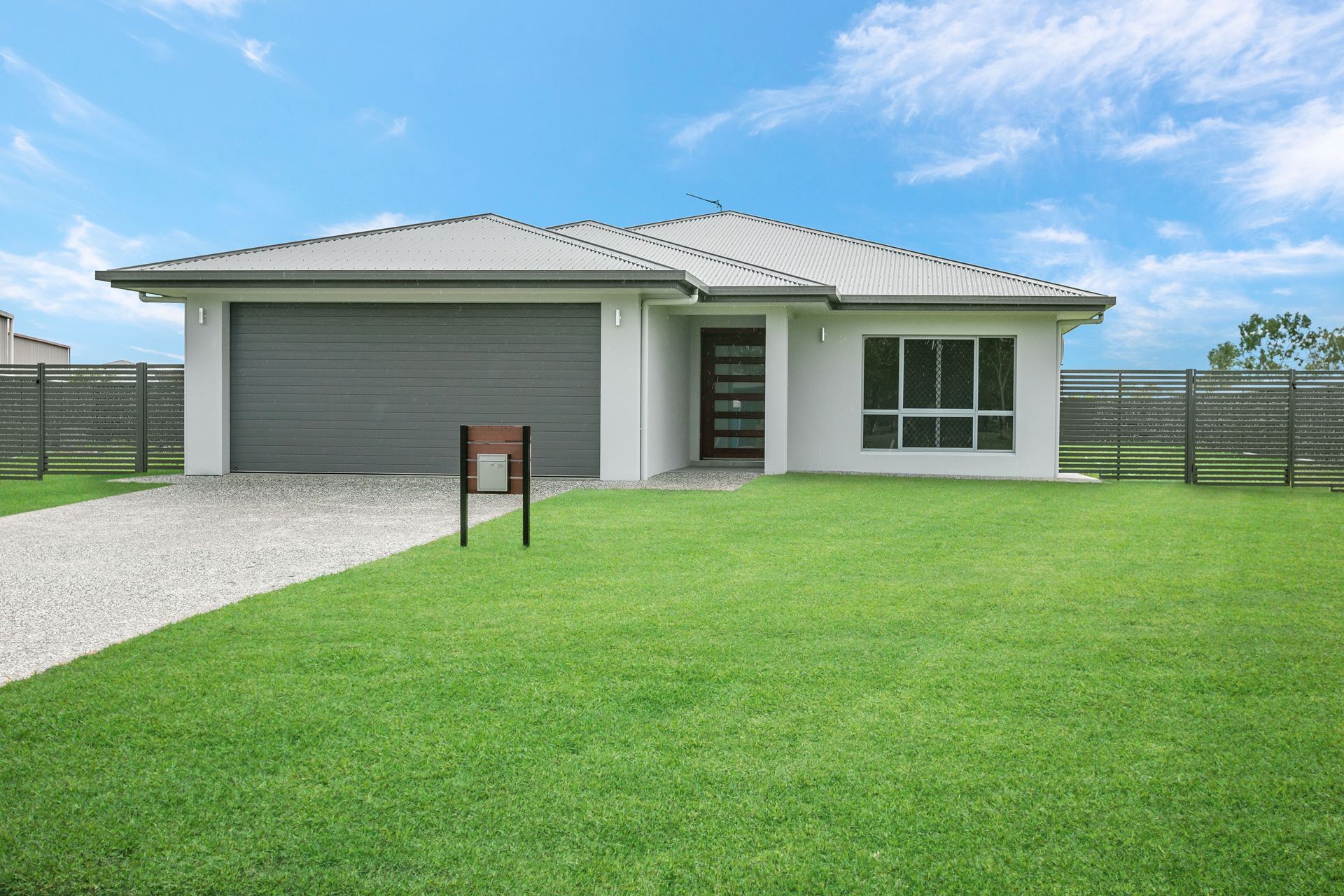 A Modern, Single-story Light-colored House With a Grey Roof and Garage Door — Ashlee Jones Homes in Gordonvale, QLD