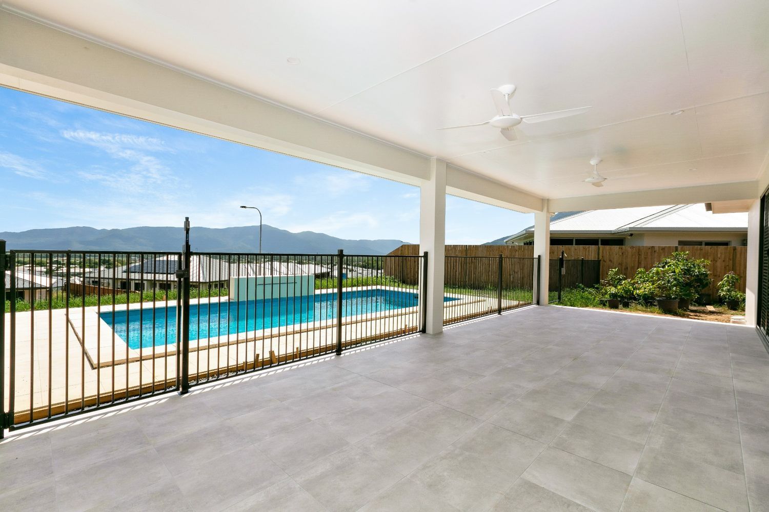 An Empty Patio With a Fence and a Pool in the Background — Ashlee Jones Homes in Gordonvale, QLD