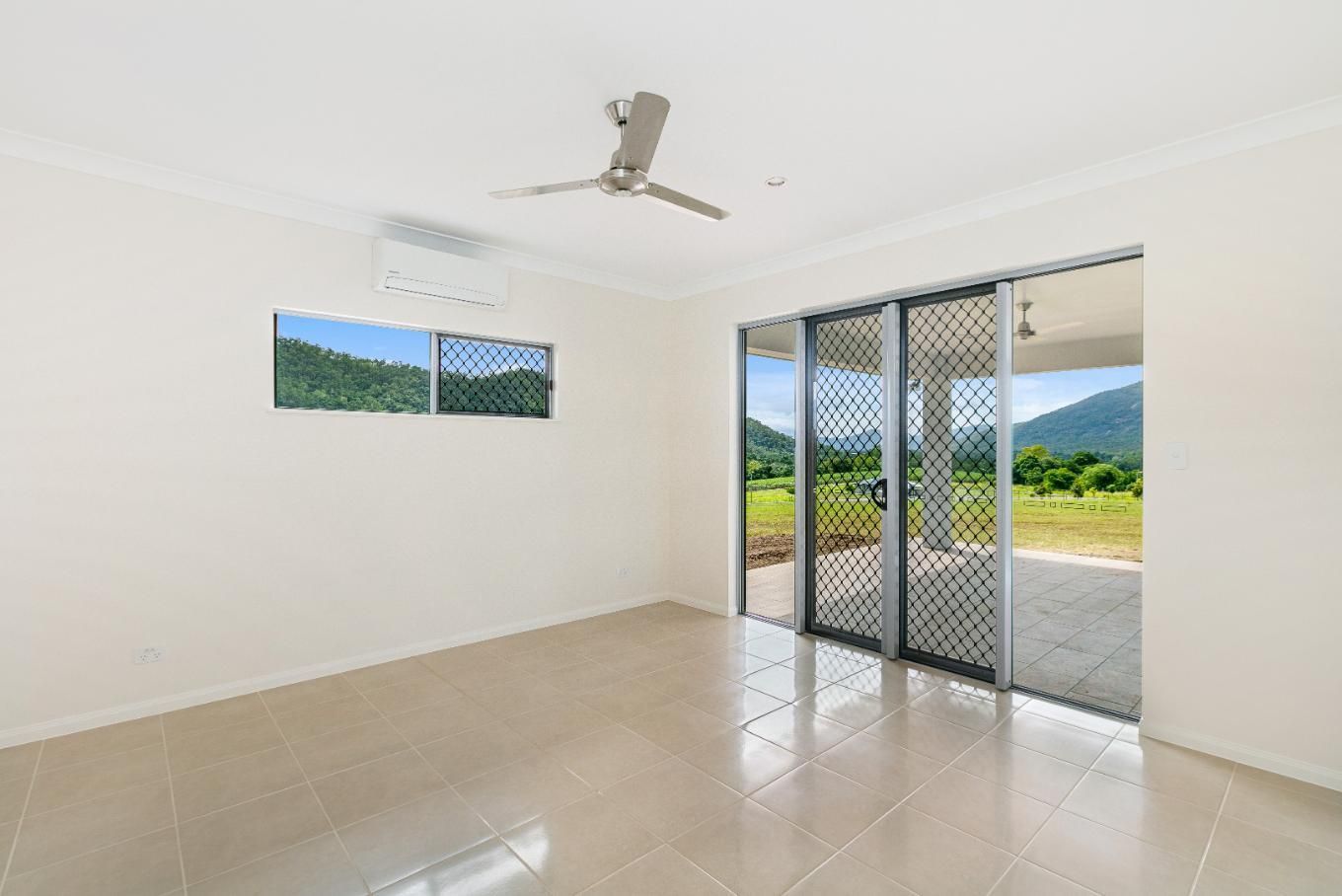 An Empty Living Room With a Ceiling Fan and Sliding Glass Doors — Ashlee Jones Homes in Gordonvale, QLD