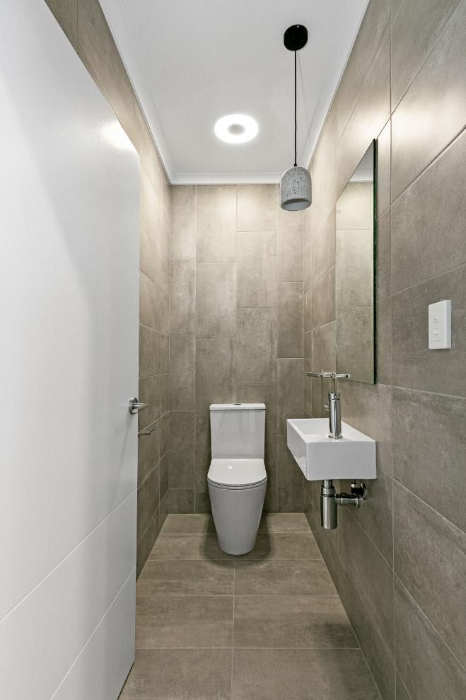 A Bathroom With a Toilet, Sink and Mirror — Ashlee Jones Homes in Gordonvale, QLD