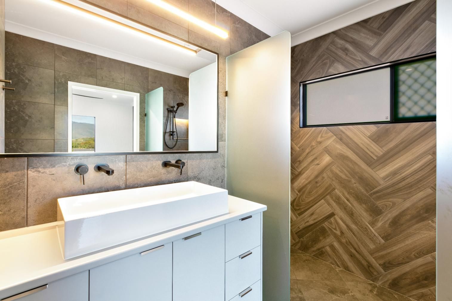 A Bathroom With a Sink, Mirror and Shower — Ashlee Jones Homes in Gordonvale, QLD